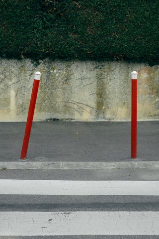 Two iron bars protecting a crosswalk with one being tilted