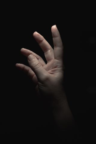 A hand reaching for the light in a dark environment