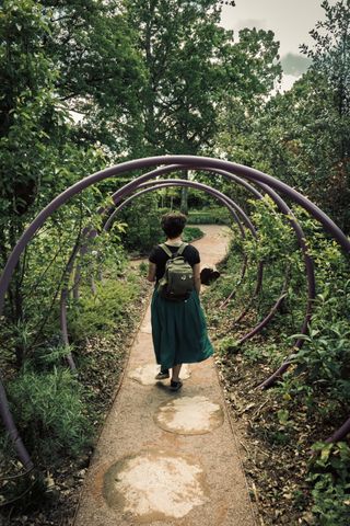 A woman walking on a path through several circles in a garden