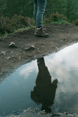 Someone standing on the top of a hill and their reflection in a puddle of water behind them